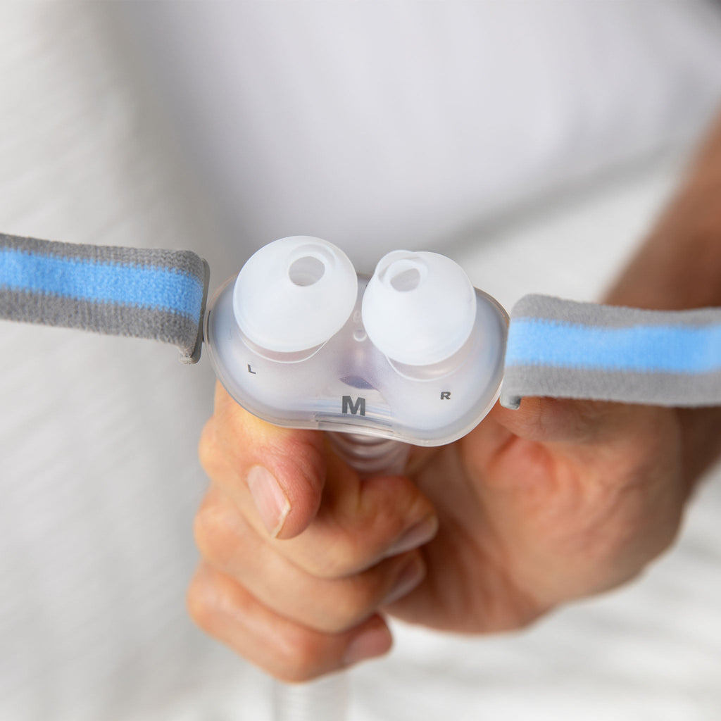 ResMed P10 nasal pillow mask held in hand, showing silicone nasal inserts and grey and blue headgear.