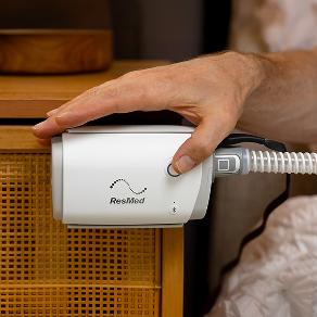 Hands holding a compact travel CPAP machine