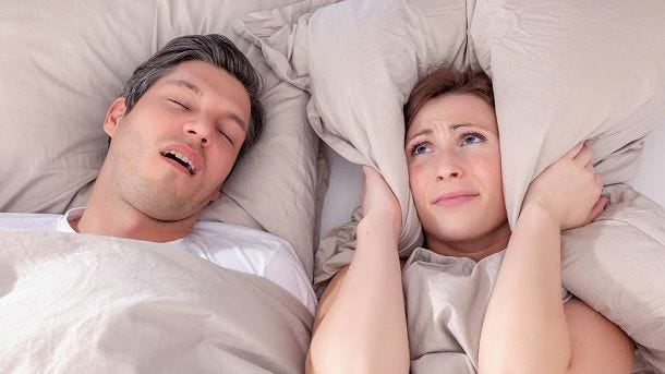 man snoring with woman holding ears