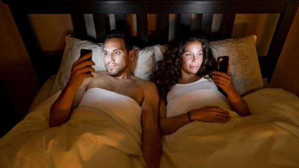 Husband And Wife Using Phones Before Sleeping