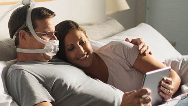 man woman in bed wearing cpap mask