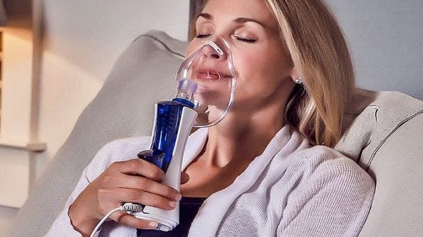 woman sitting on couch using nebulizer