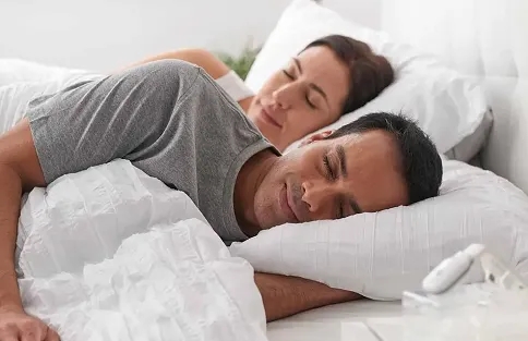 Woman lying in bed using an alternative to CPAP machine. 