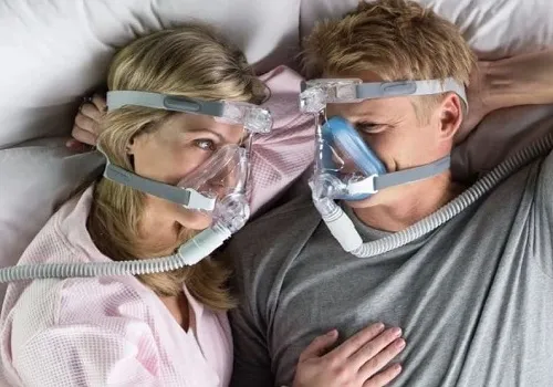 Couple in bed wearing  CPAP masks. 