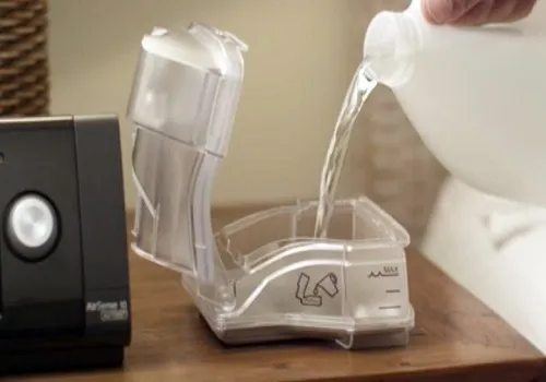 Pouring water into CPAP humidifier.