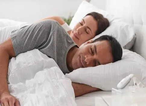 Woman lying in bed using an alternative to CPAP machine. 