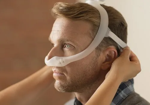 Man wearing CPAP mask with headgear. 