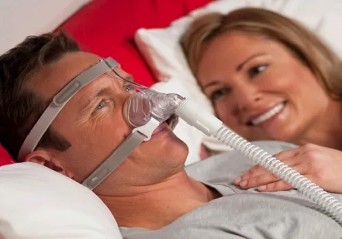 Couple lying in bed with a CPAP mask. 