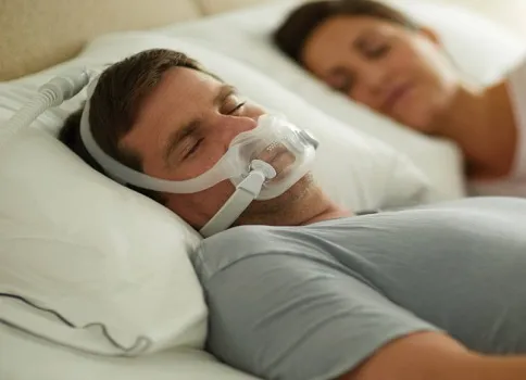 Man with CPAP mask laying in bed with woman. 